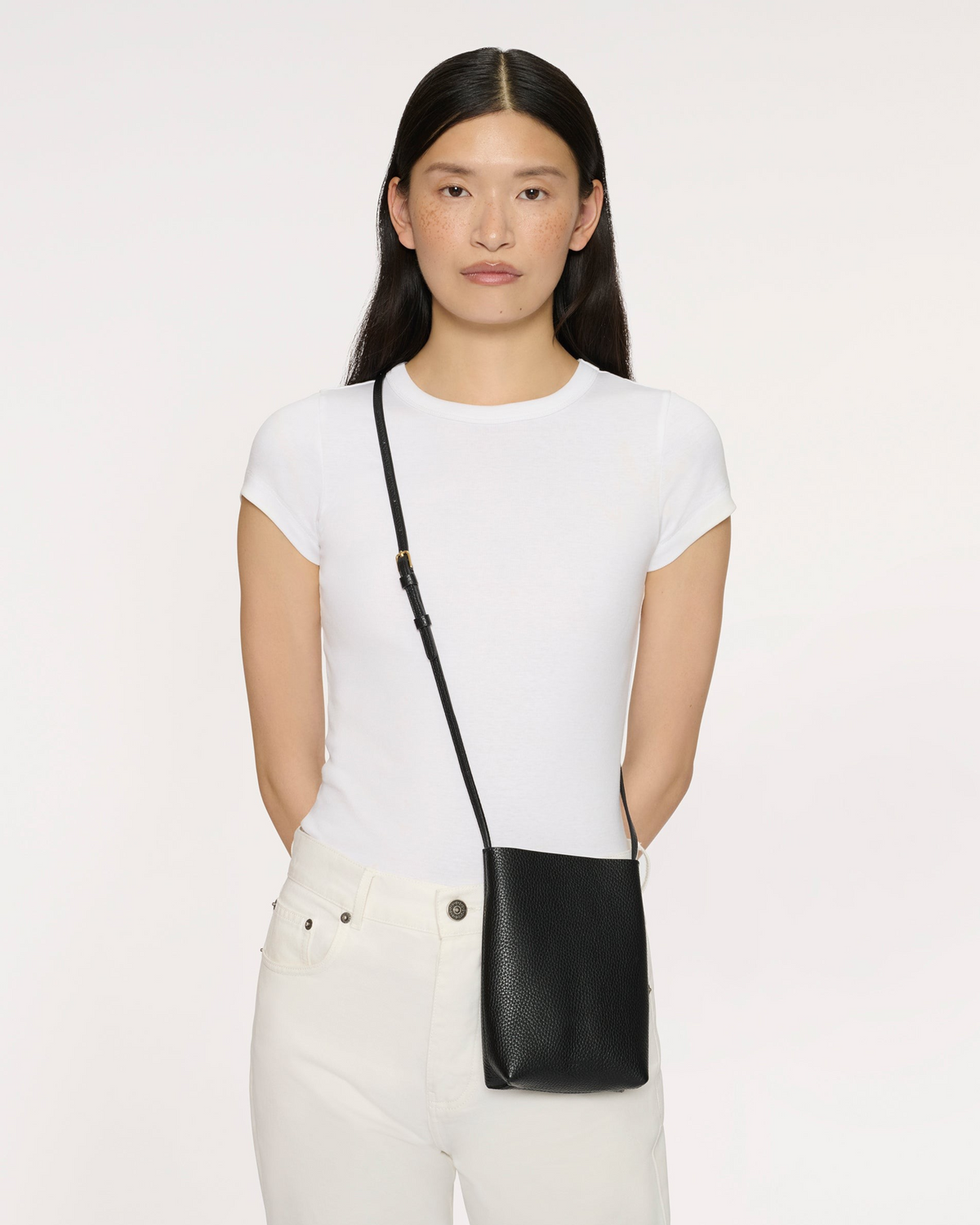 Weldun Mansur Gavriel Everyday Cabas crossbody bag in black pebbled leather worn by a model in a white t-shirt