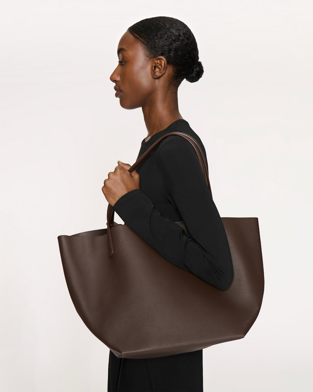 Weldun Mansur Gavriel Everyday Soft Tote in ebony brown Italian calf leather carried over the shoulder by a model.