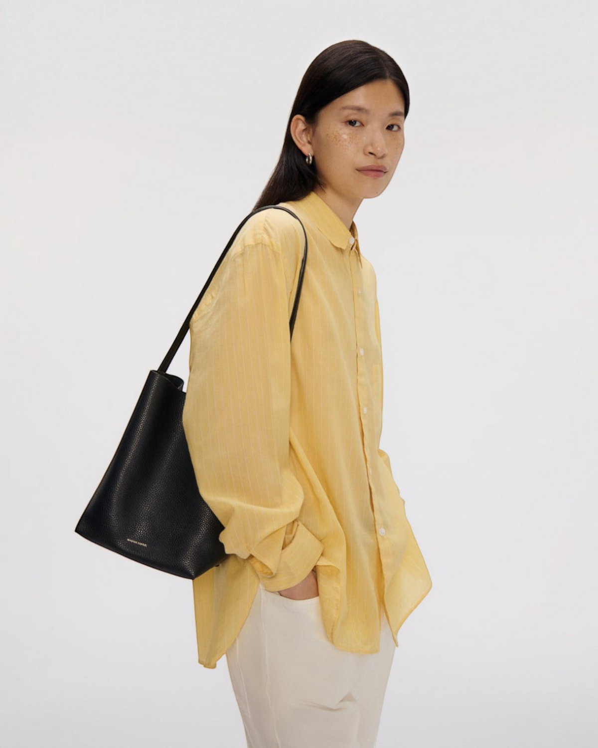 Weldun model wearing a black Mansur Gavriel Small Everyday Cabas leather shoulder bag with elongated handles