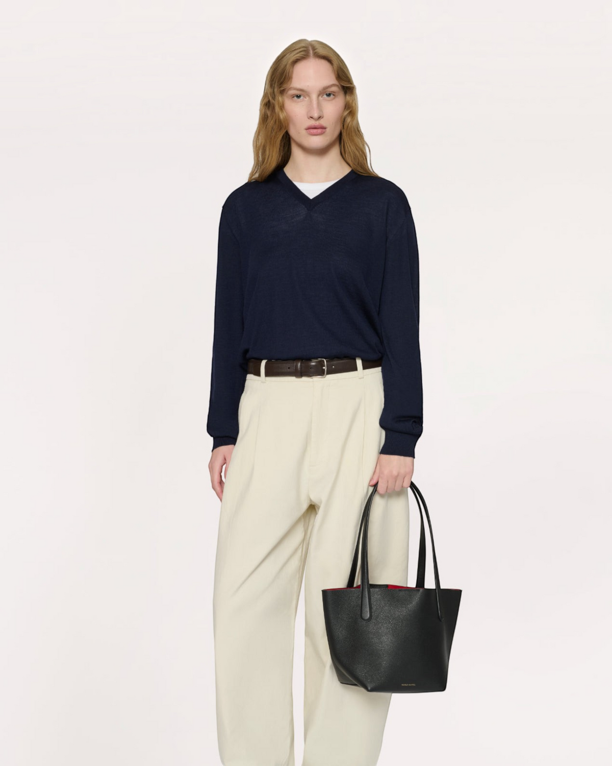 Weldun Mansur Gavriel small everyday soft black calf leather tote with red interior held by a model