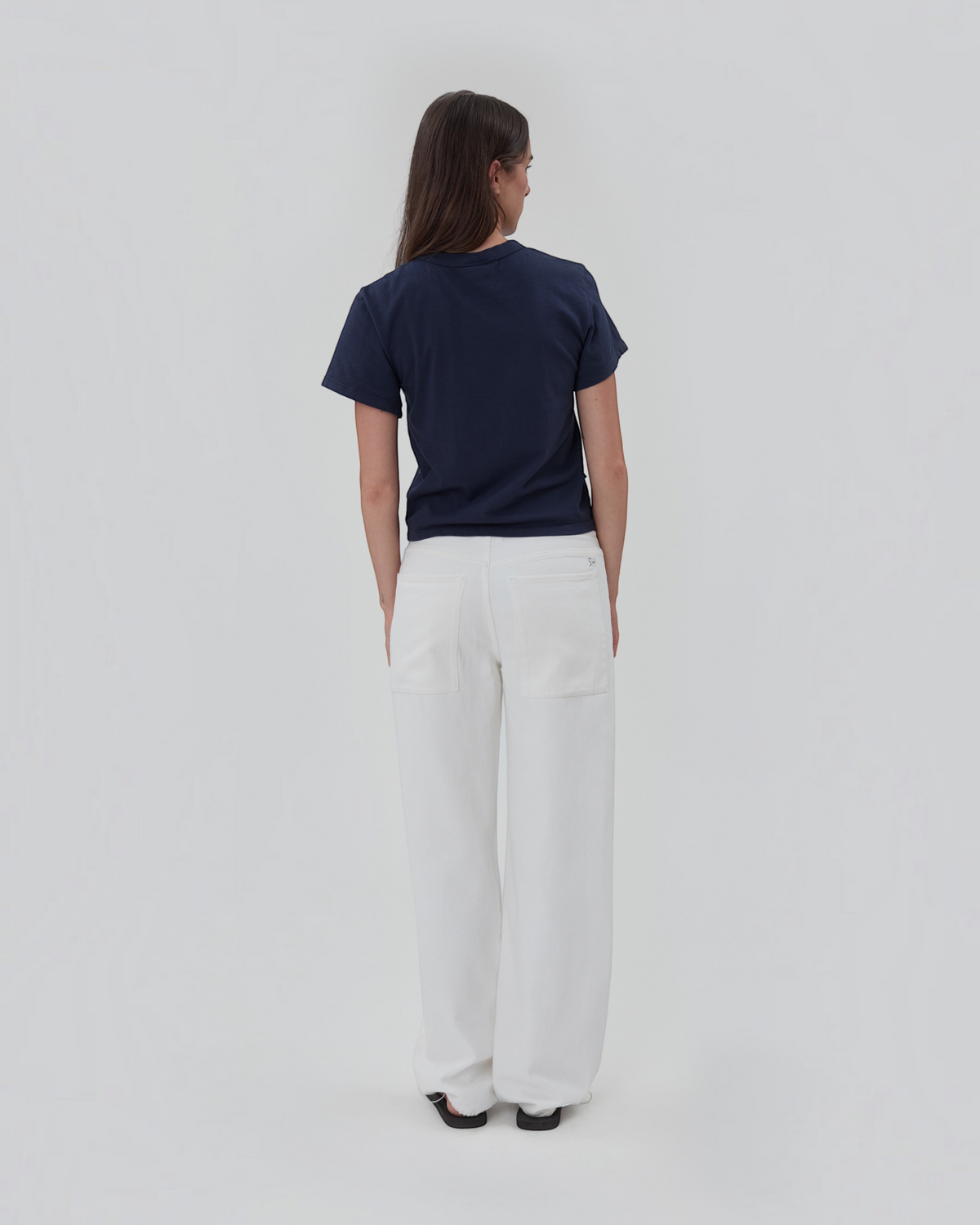 Weldun Still Here navy blue cotton short sleeve Henley shirt worn with white wide-leg trousers, back view