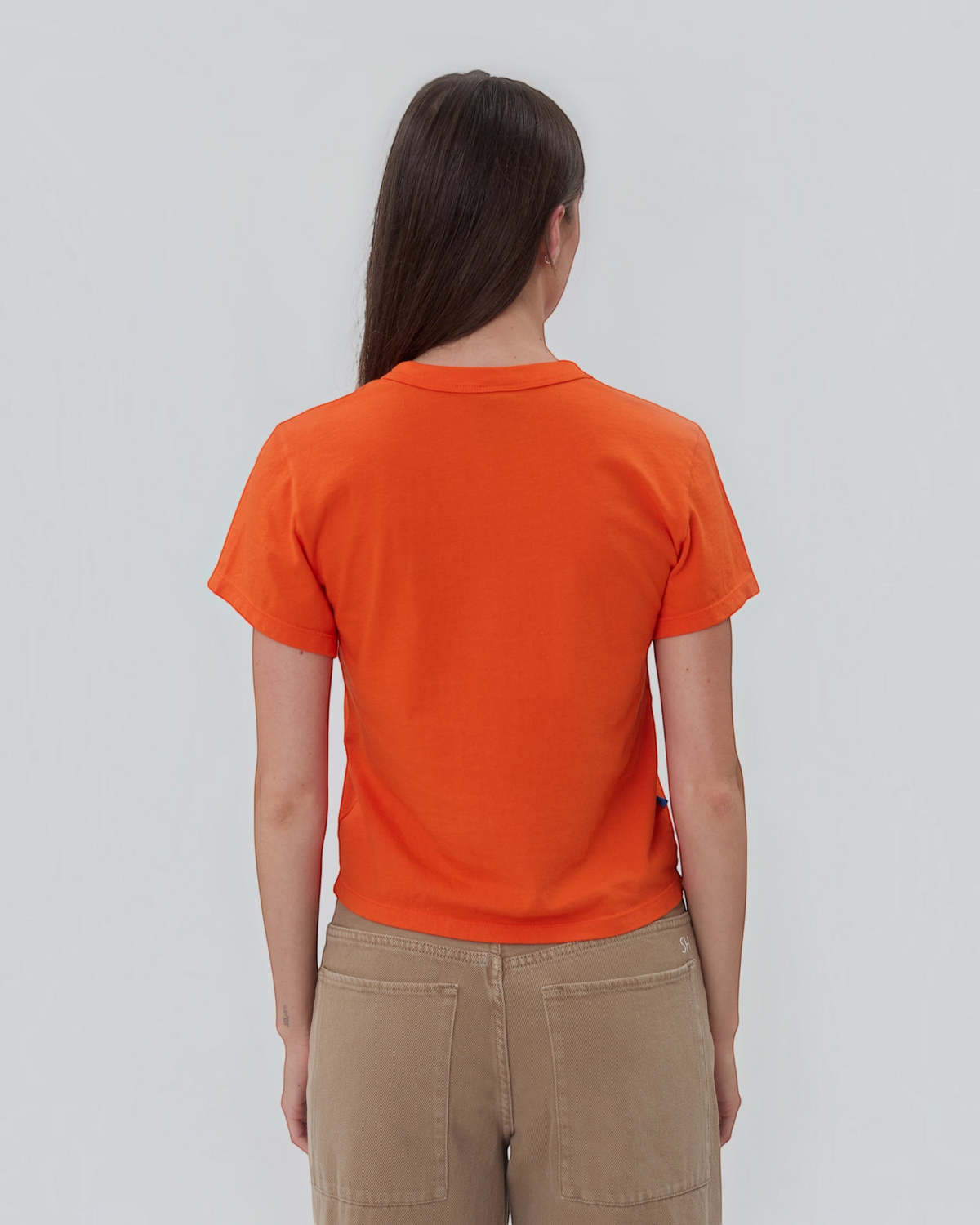 Back view of a model wearing a Weldun orange short sleeve cotton Henley shirt with a relaxed fit.