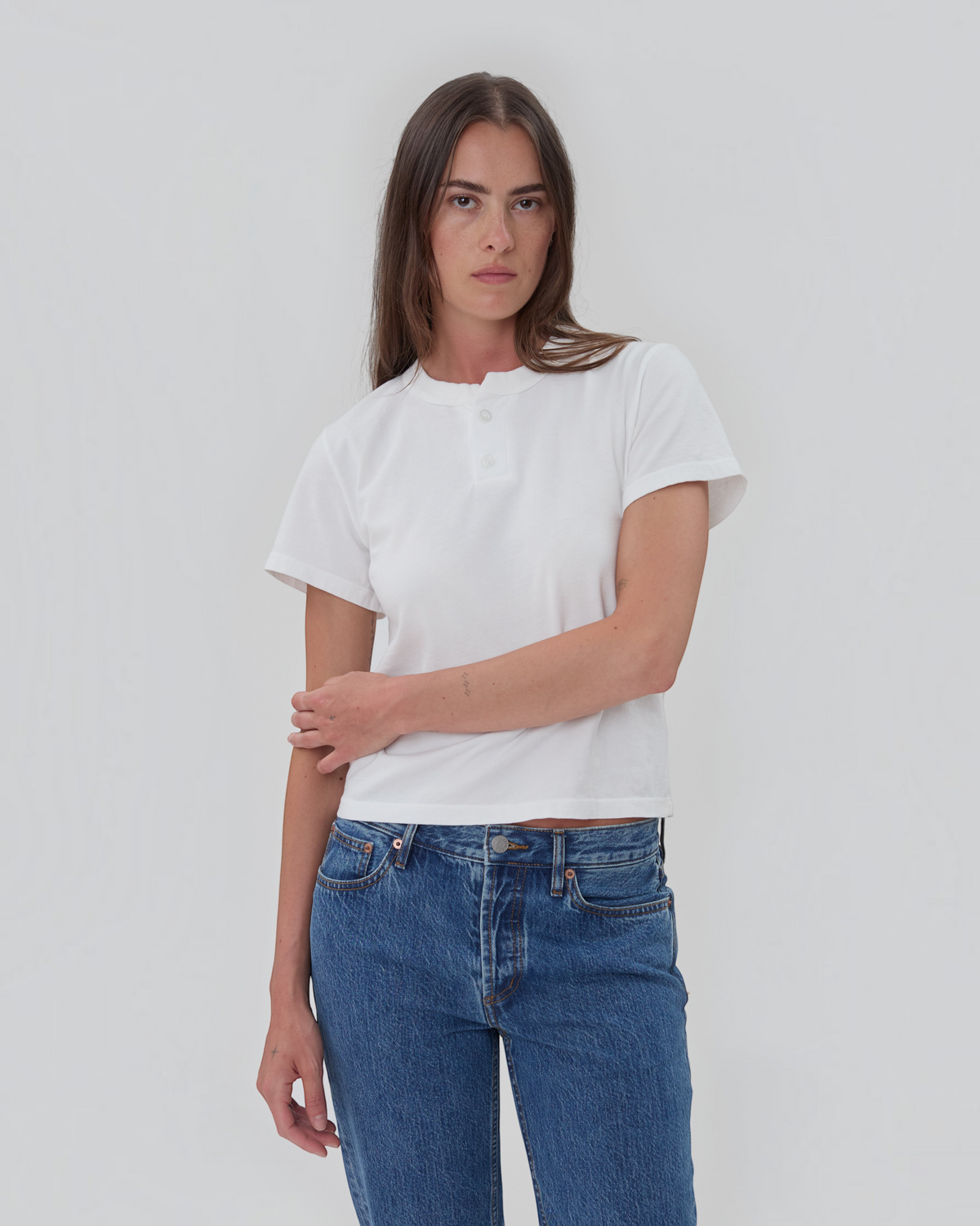 Weldun white 100% cotton short sleeve Henley shirt with a two-button placket worn by a woman with blue jeans.