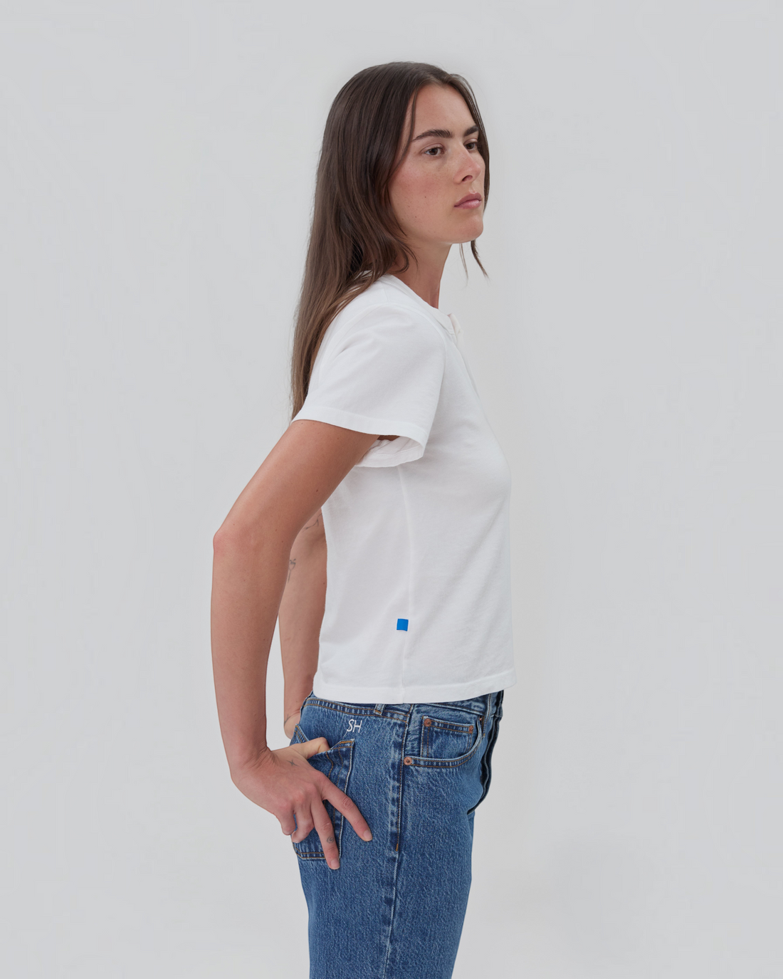 Weldun Still Here white short sleeve cotton Henley shirt with two-button placket and blue side tab on a model