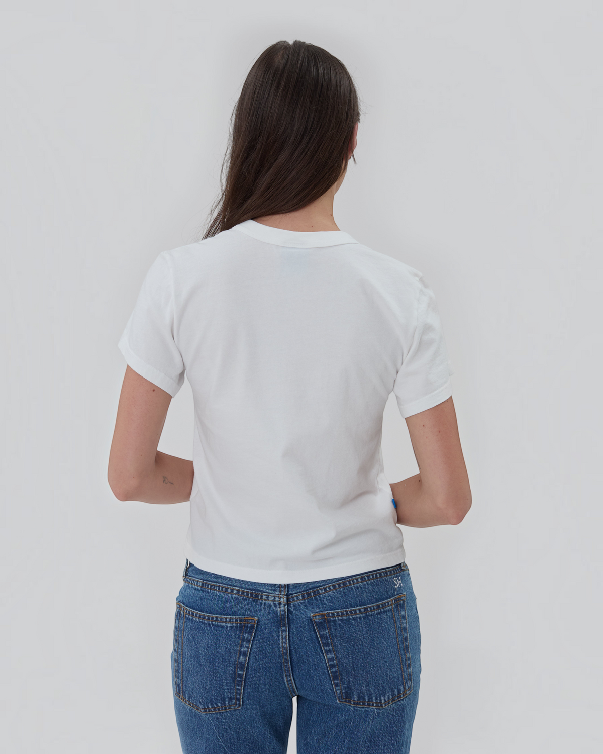 Weldun white short sleeve cotton Henley shirt worn by a woman, back view showing relaxed fit and blue side tab.