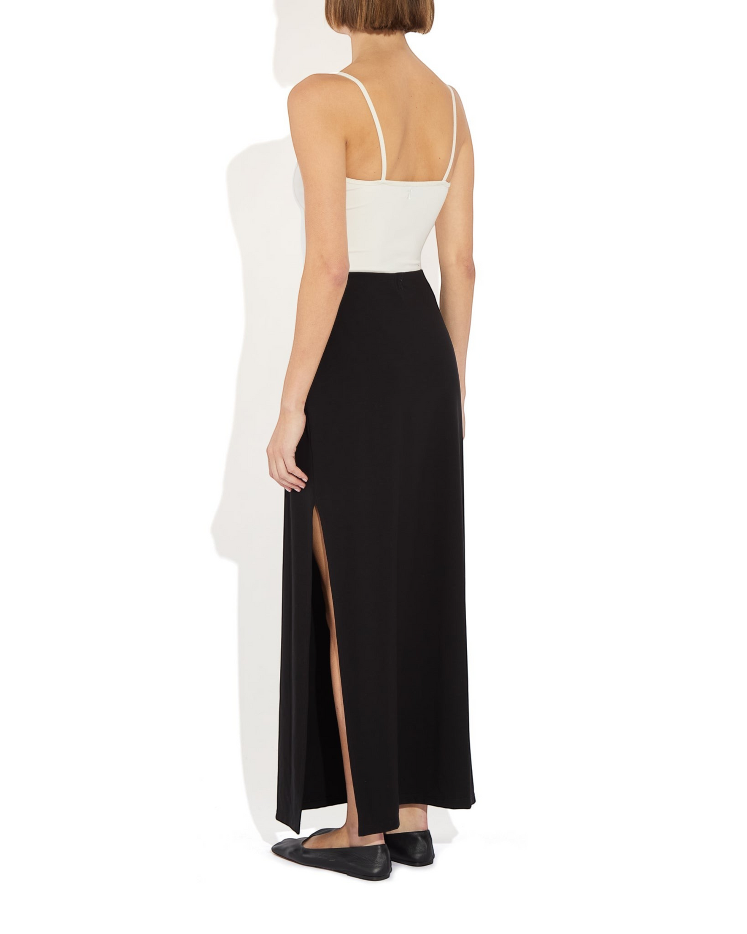 Weldun Ashley skirt in black with a side slit, worn with a white tank top in a minimalist column silhouette