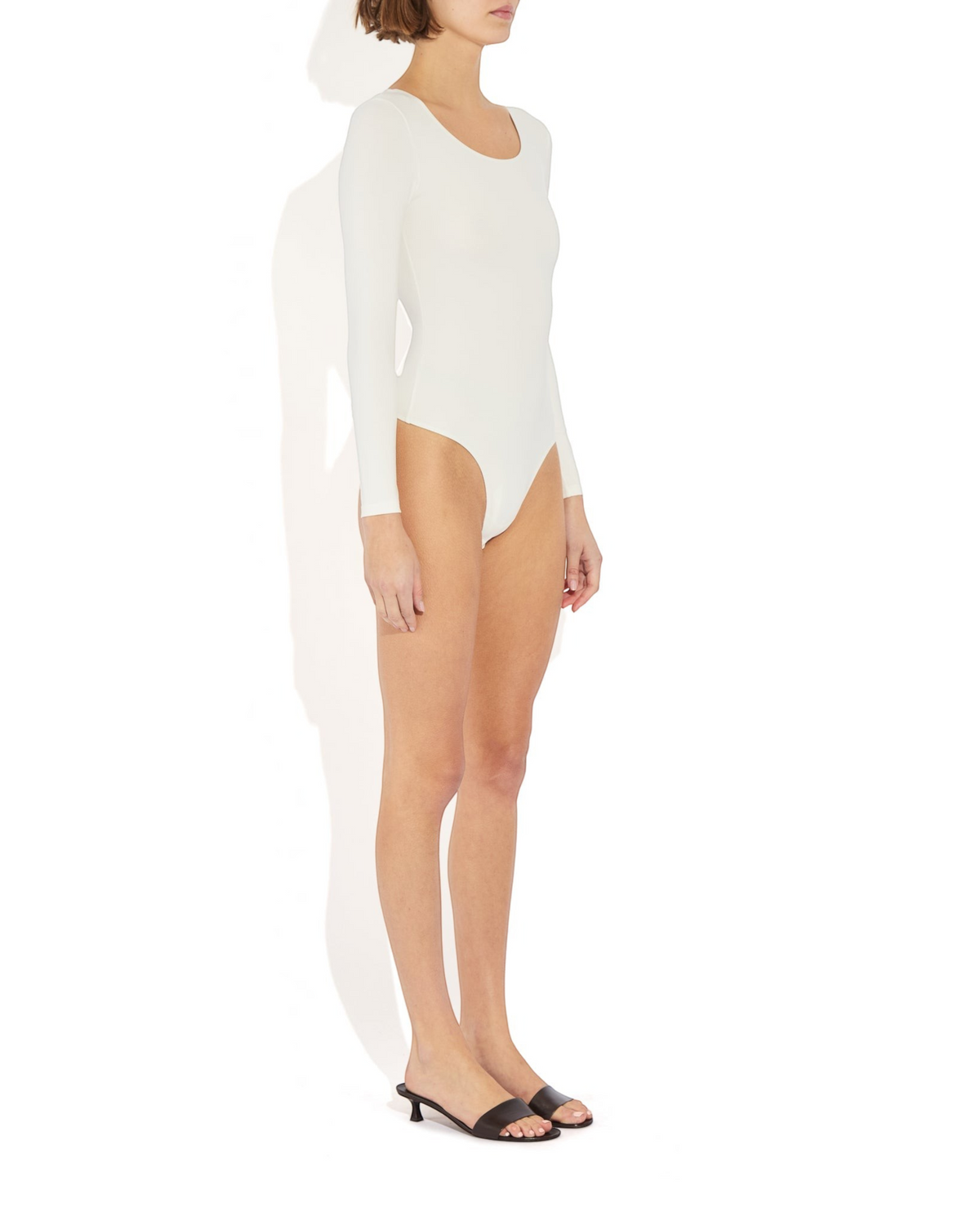 Weldun Donna long-sleeve white stretch-knit bodysuit with a scoop neckline and cheeky cut, side view.
