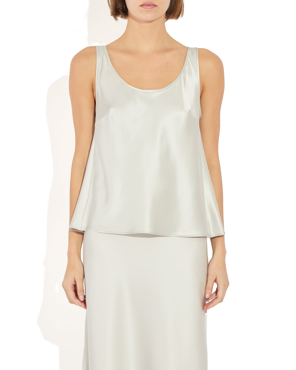 Weldun Karen Tank in silver stretch silk with a scooped neckline and fluid bias-cut drape on a model