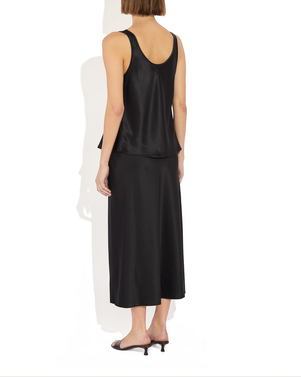 Weldun Karen Tank in black stretch silk with a scooped neckline, shown from the back on a model.