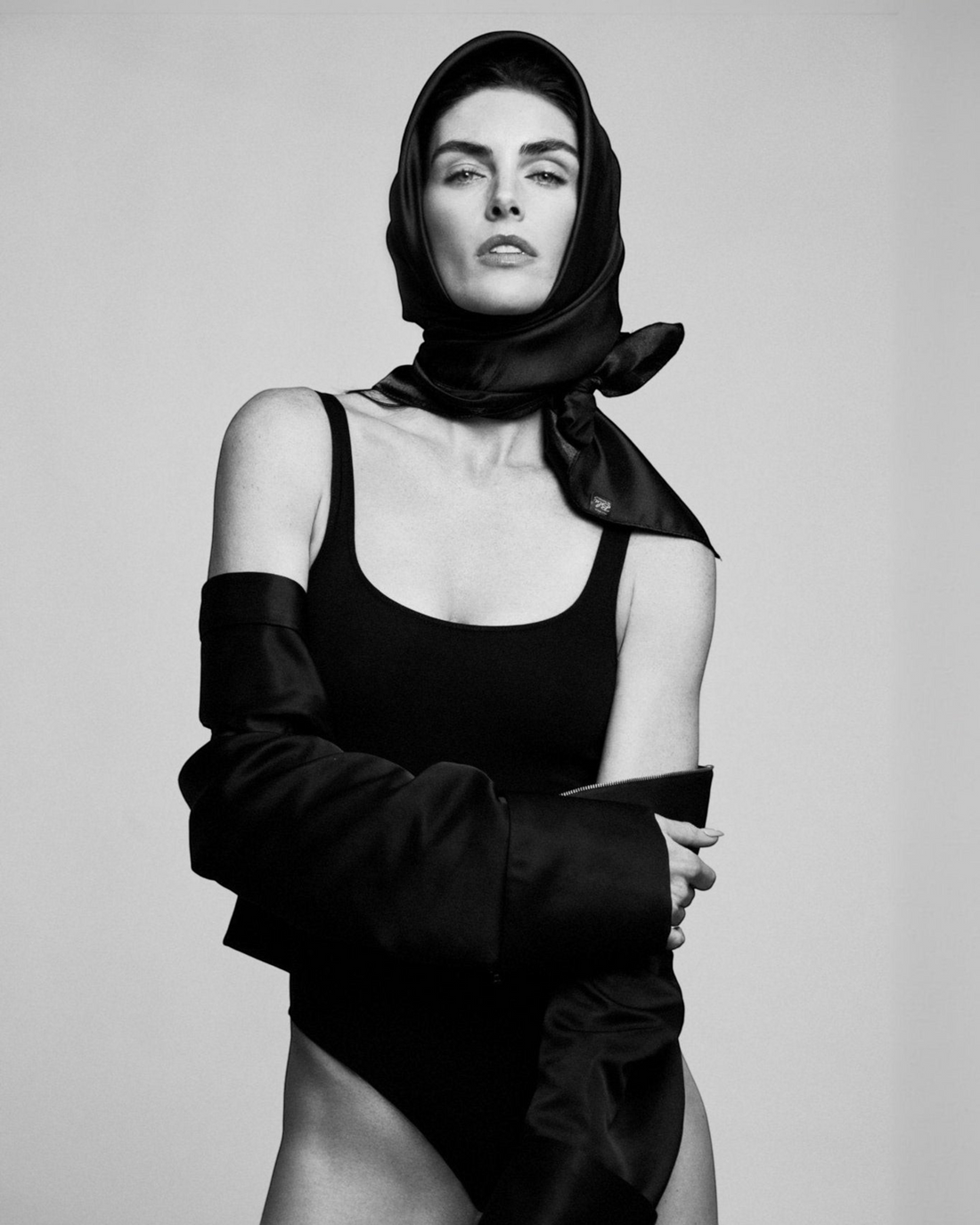 Weldun Lisa Bodysuit in black with a scoop neckline, worn by a model styled with a headscarf in a studio portrait.