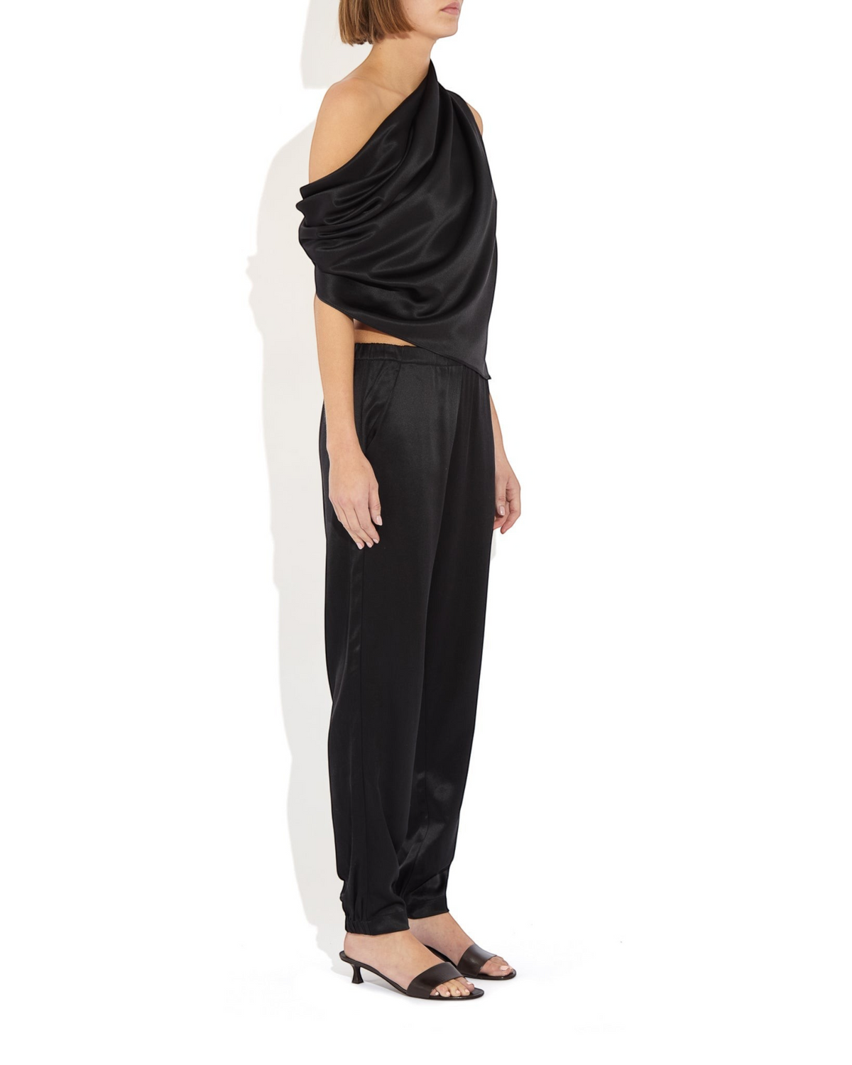 Weldun Rebecca Jogger in black silk with elastic waistband and tapered leg, worn by a model in a side profile view.