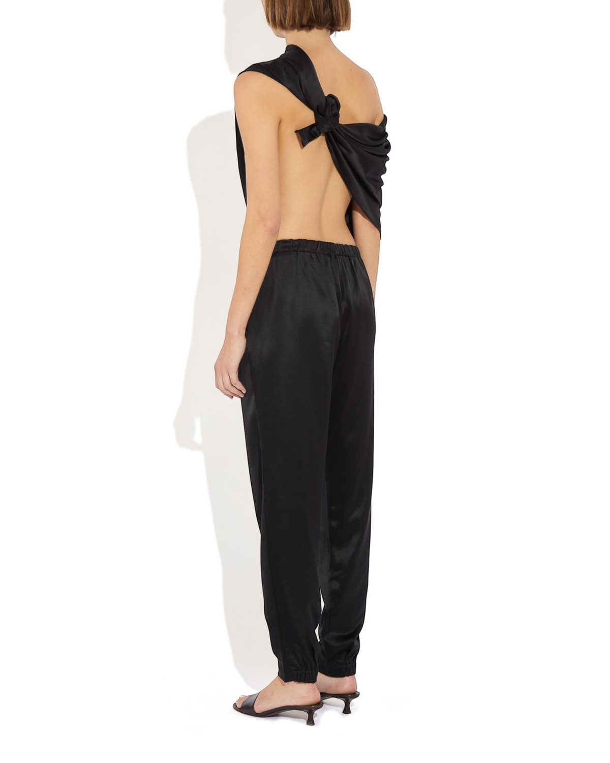 Model wearing Weldun black silk Rebecca Joggers with elastic cuffs and waistband, viewed from the back.