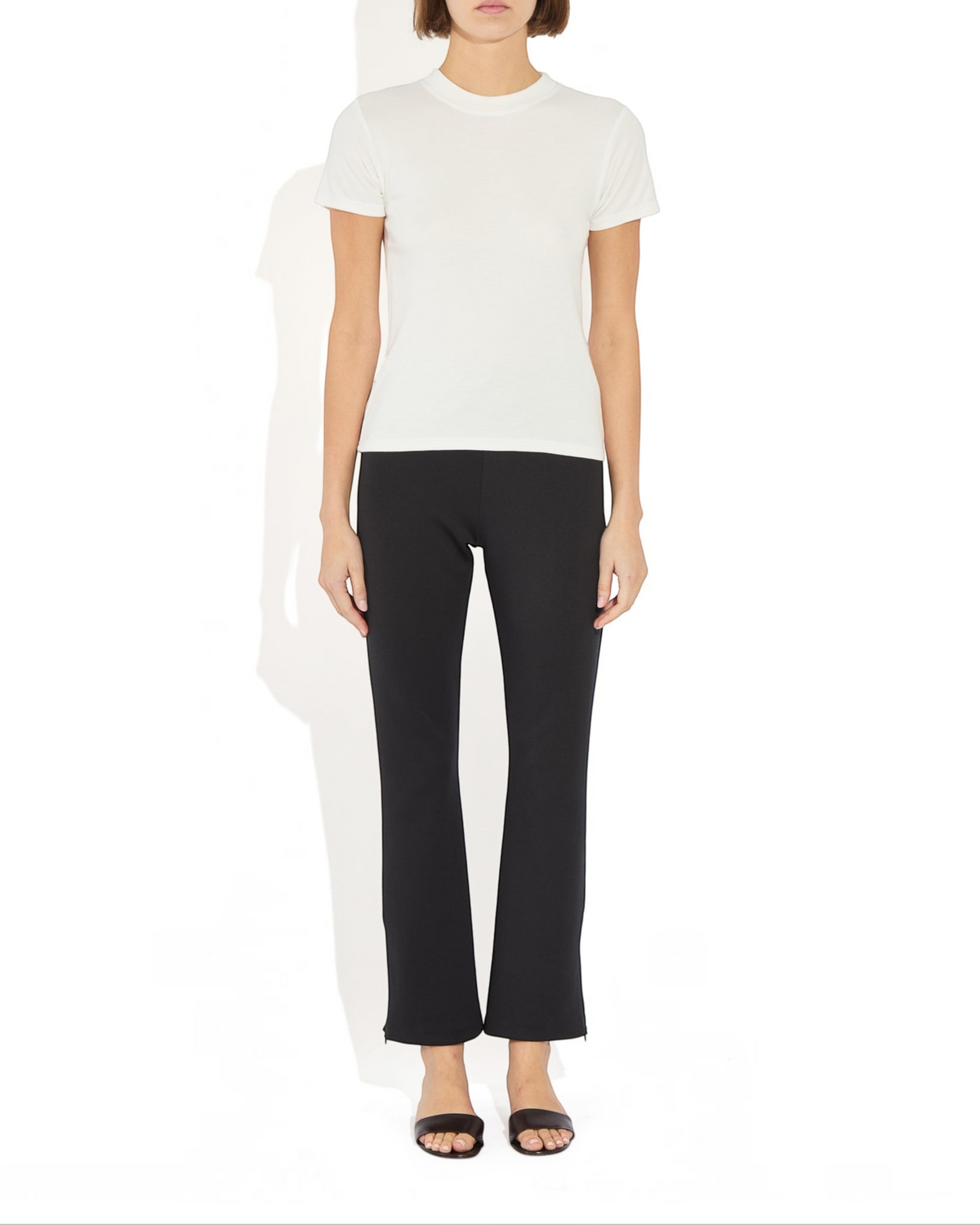 Weldun Sarah Pant in black recycled stretch fabric with side hem zippers worn by a model with a white t-shirt
