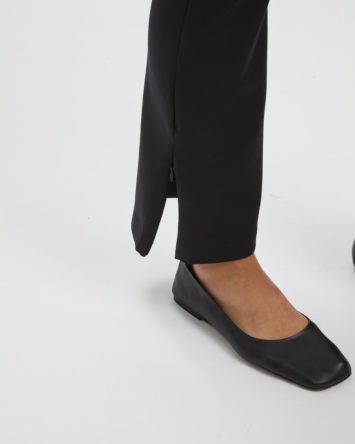 Weldun Sarah Pant in black recycled polyester with a functional side zipper hem detail on a model