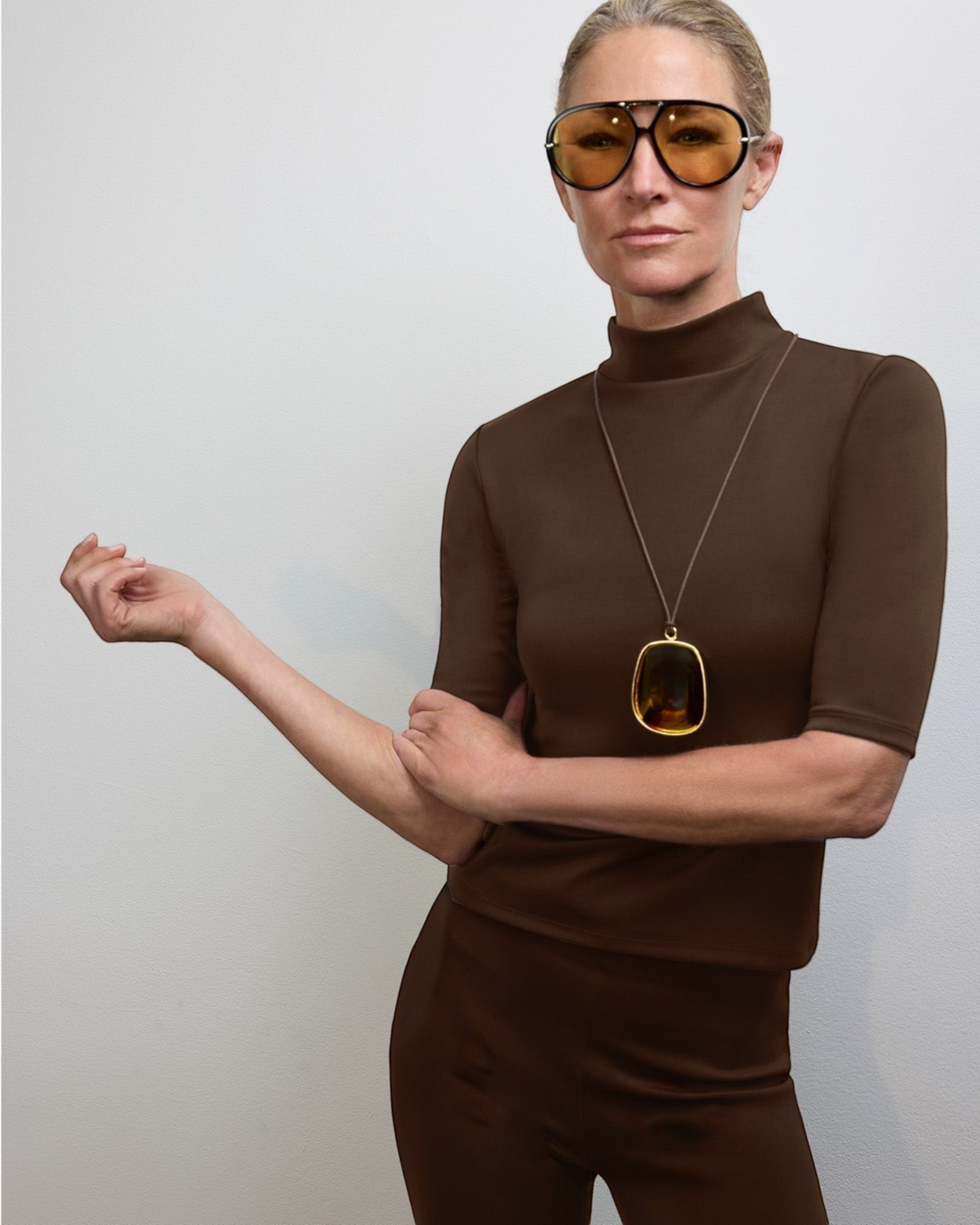 Weldun Sarah Pant in dark brown recycled stretch fabric worn by a model with a matching top and amber pendant