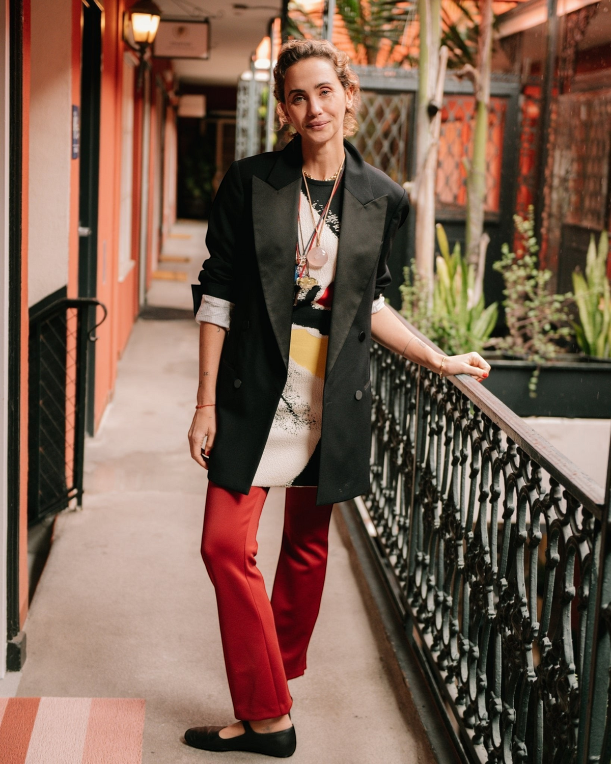 Weldun Sarah Pant in red, a pull-on recycled polyester pant with side hem zippers worn by a woman in a blazer