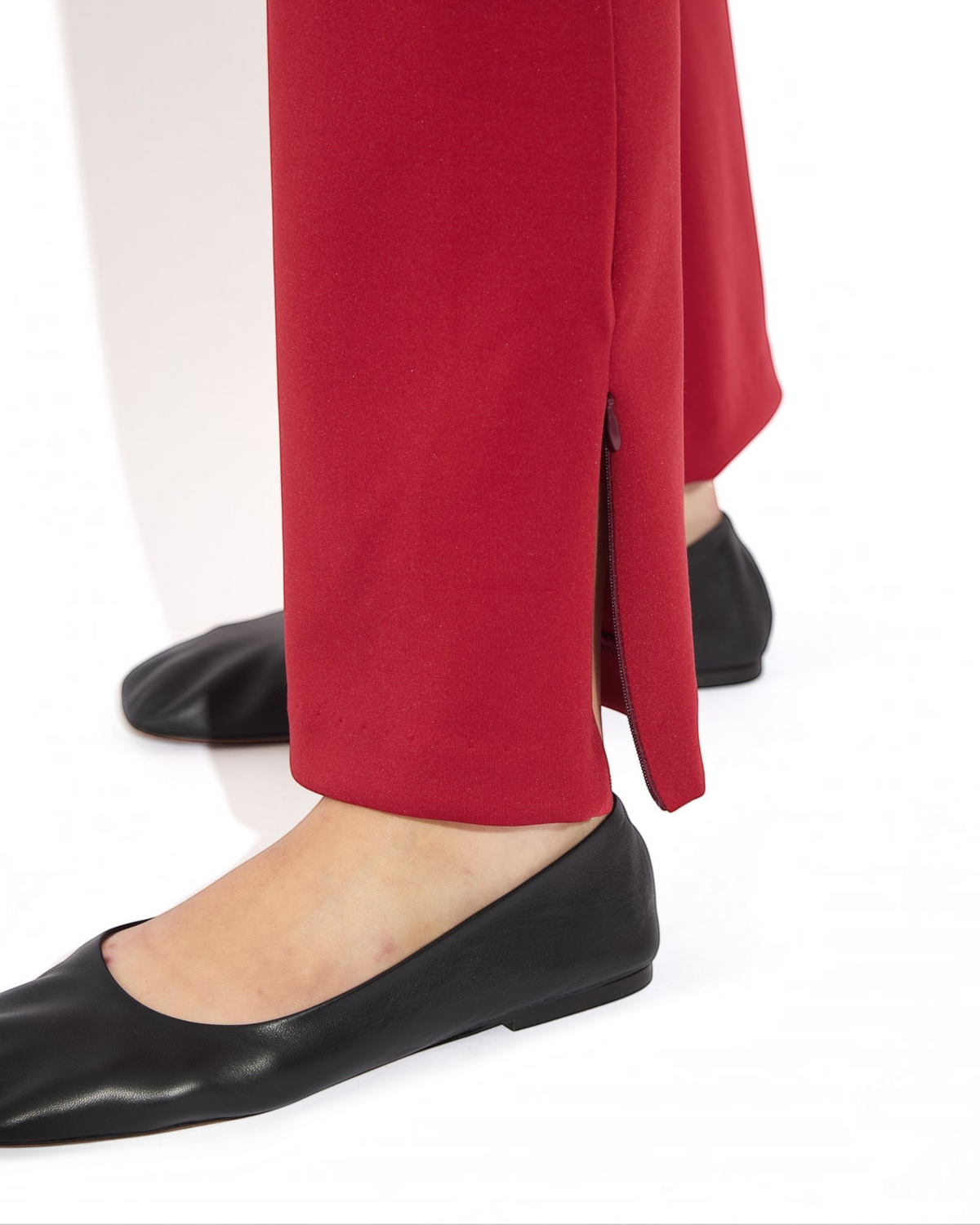 Weldun Sarah Pant in red recycled polyester with a functional side zipper hem detail worn with black flats