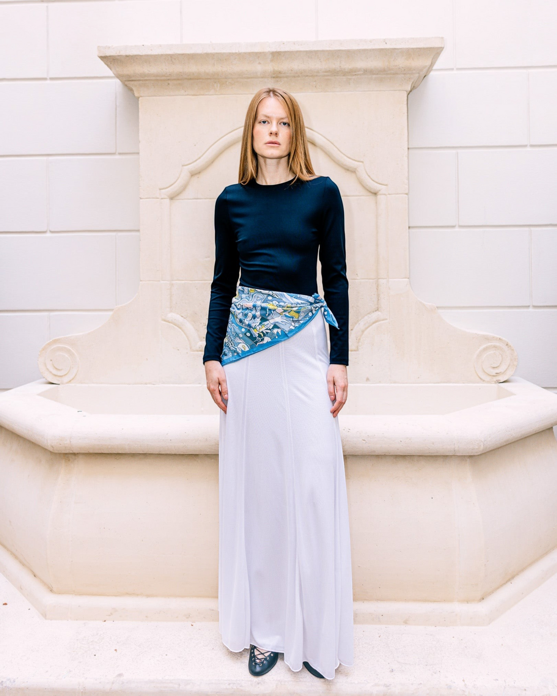 Weldun Semi-Sheer Olivia maxi skirt in white lyocell with elastic waistband, worn by a model in a stone courtyard.