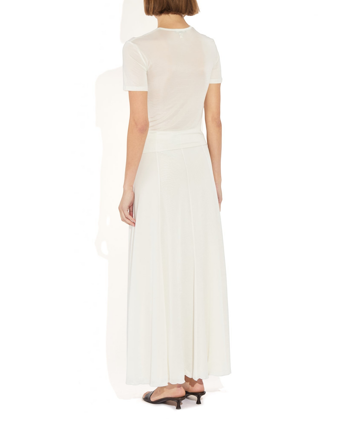 Back view of a model wearing the Weldun Semi-Sheer Olivia maxi skirt in white, featuring a fluid, layered design.
