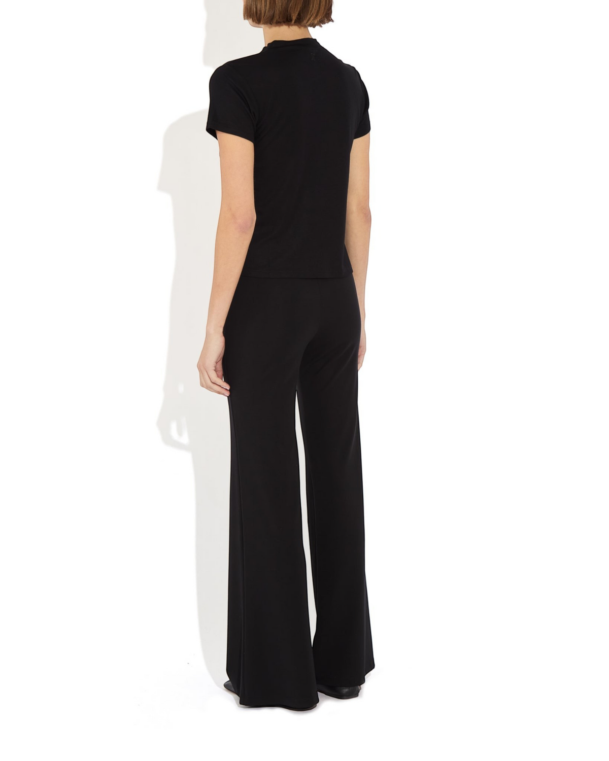 Model wearing Weldun Tessa Long Pant in black with a high elasticated waist and fluid flare leg design.