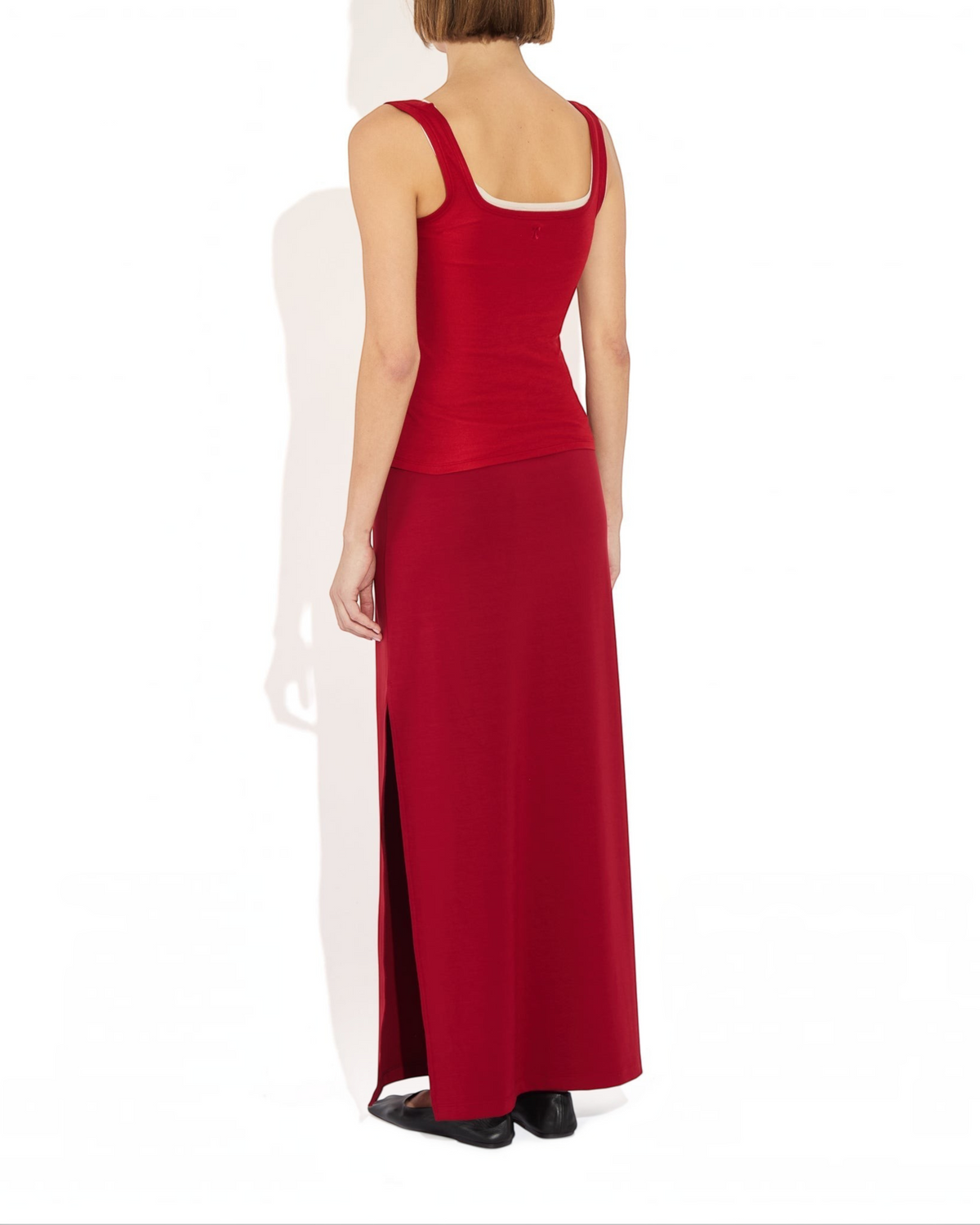 Weldun Ashley Skirt in red, a minimal column-silhouette pull-on skirt with a side slit, worn by a model from behind.