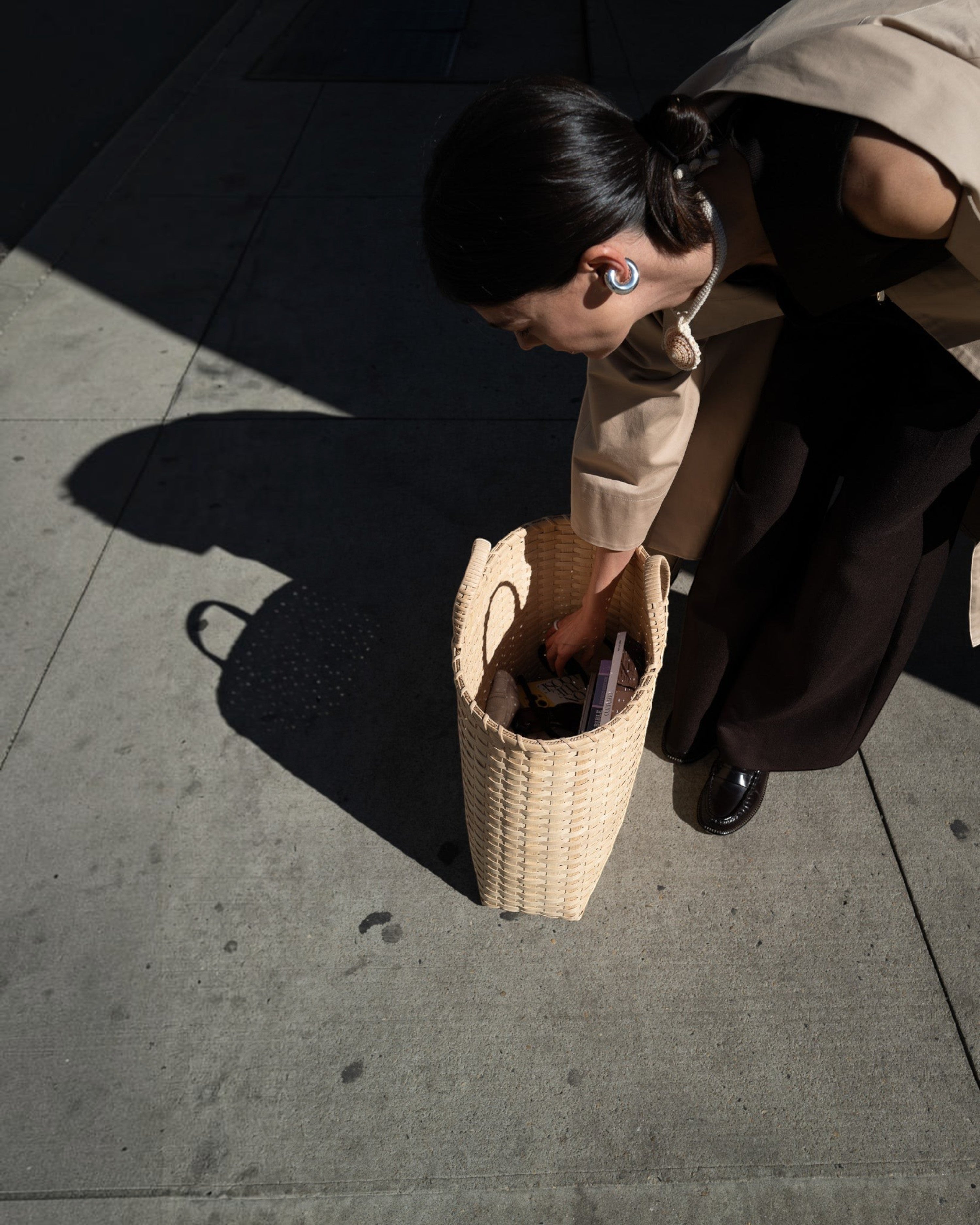Weldun Big Shopper oversized rattan basket bag held by a woman on a city sidewalk in natural light