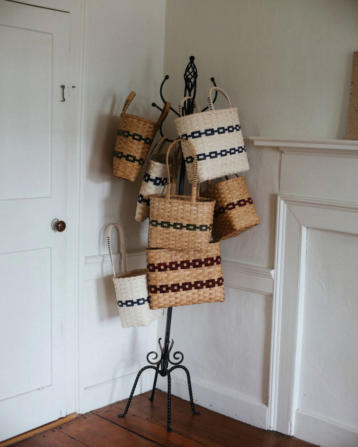 Weldun New England woven rattan shopping baskets in various sizes and patterns hanging on a decorative metal stand.