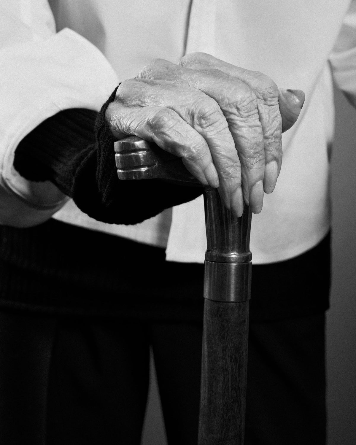 Gloria Steinem's hands resting on a walking cane, in black and white