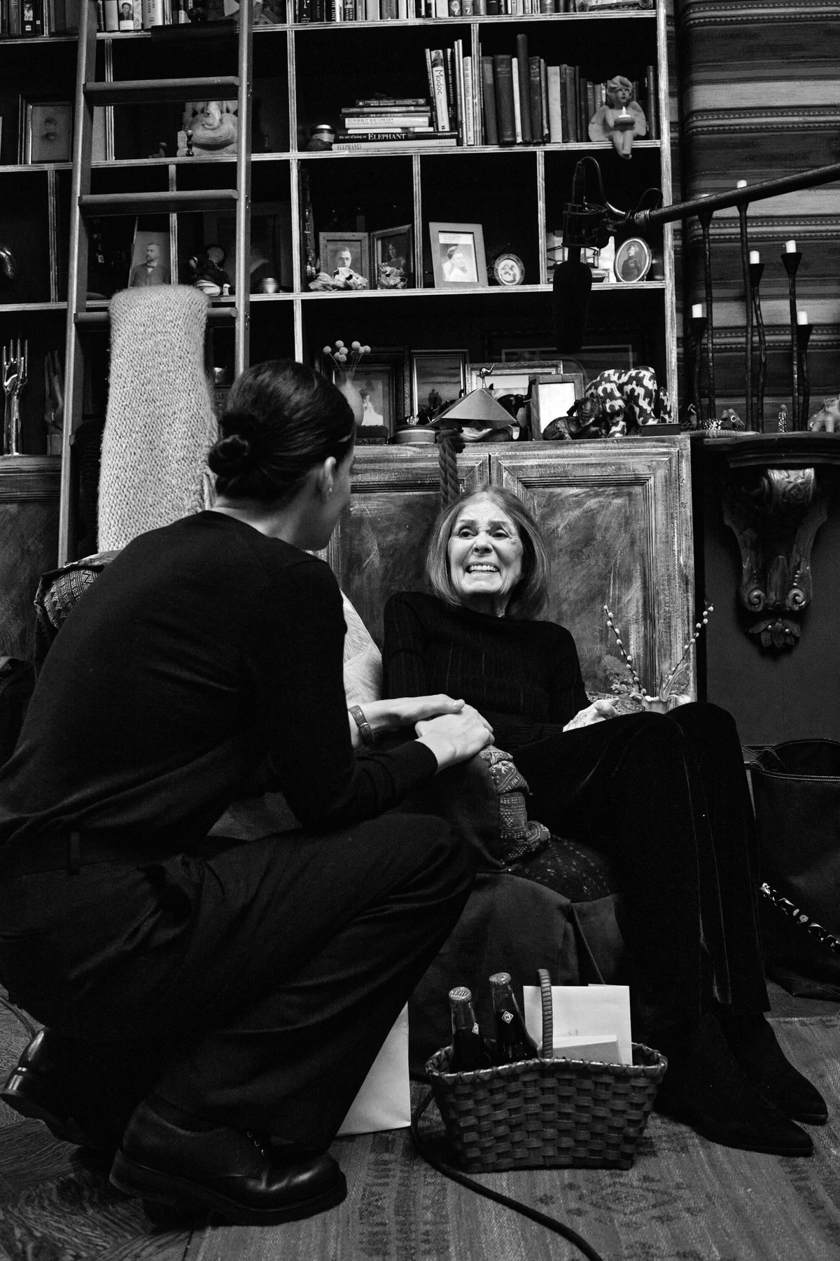 Gloria Steinem laughing in conversation at home, in front of a bookcase