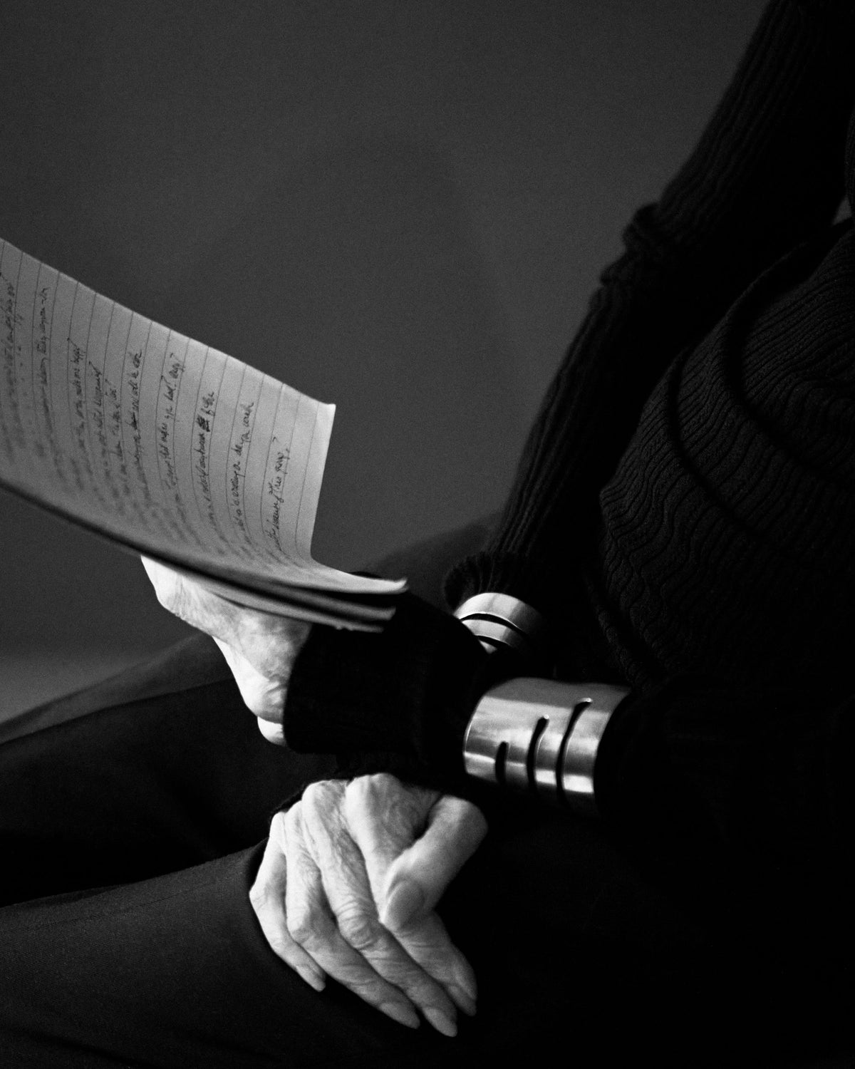 Gloria Steinem's hands with silver cuffs, holding handwritten notes